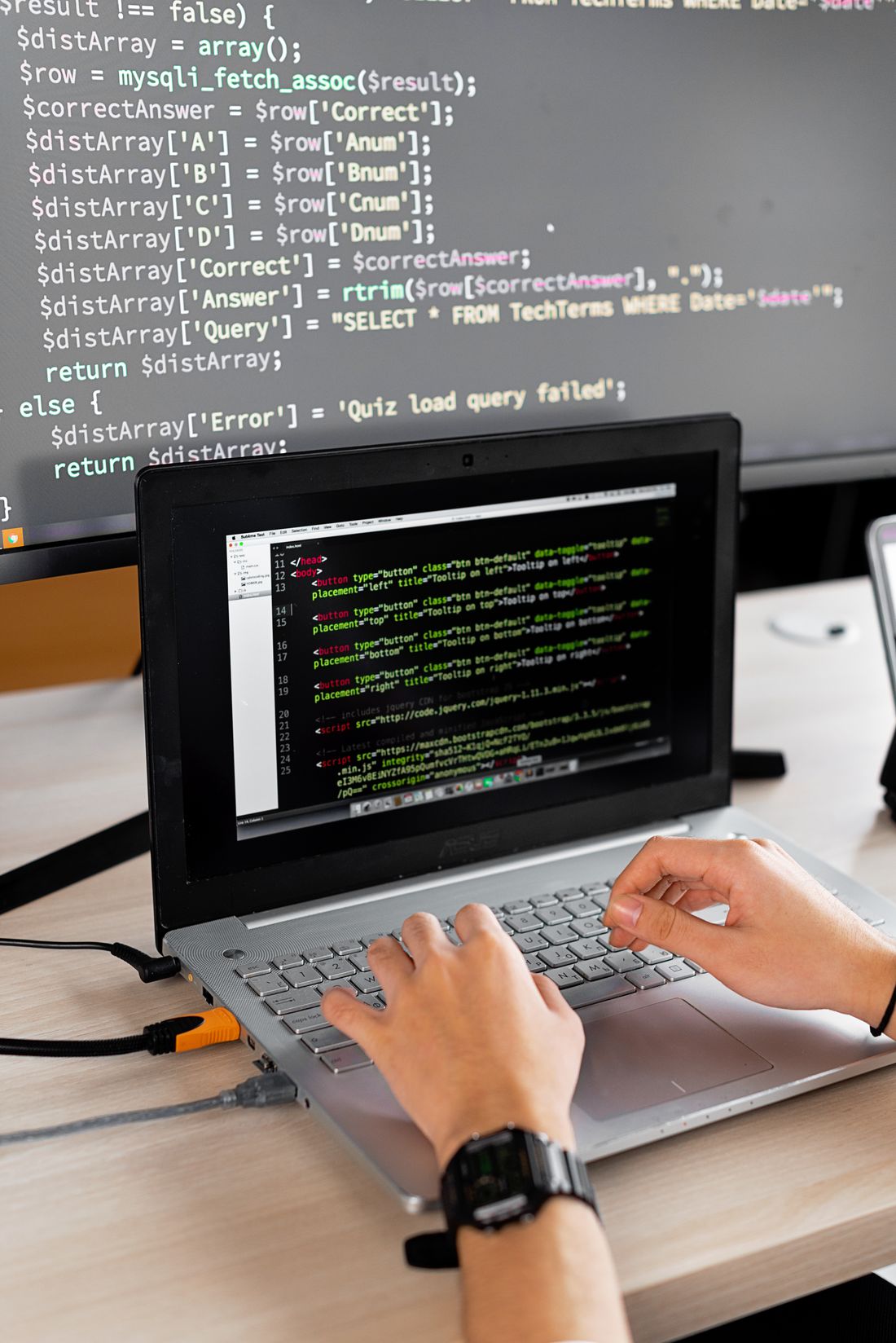 A software developer working at a laptop and an external monitor